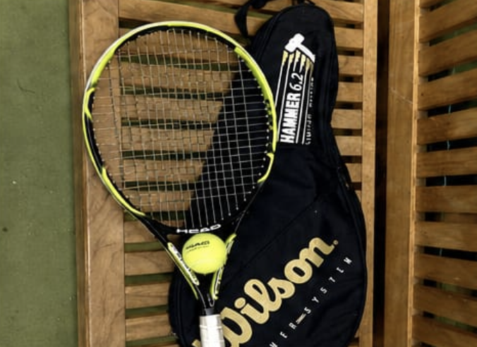 A tennis racket and ball resting against a Wilson kit bag